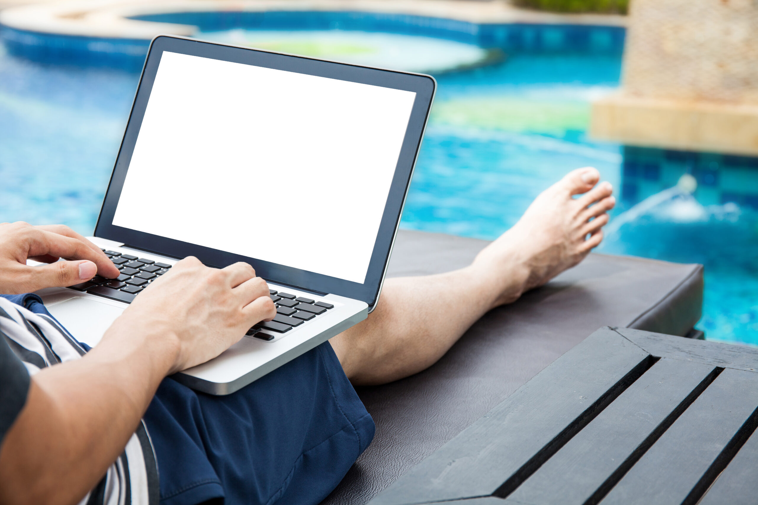 Person working on a laptop besides a pool